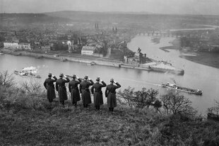 Sechs Soldaten salutieren am Rhein mit Blick auf Koblenz am gegenüberliegenden Flussufer