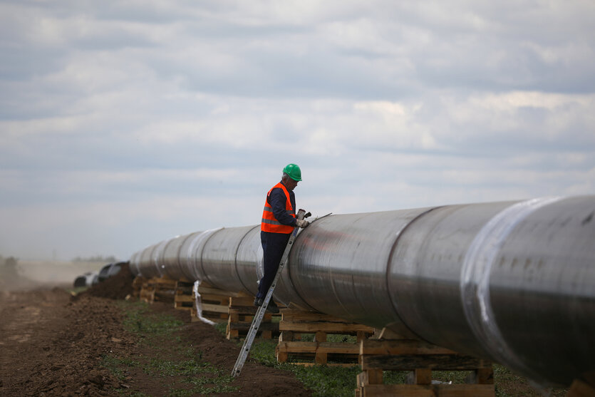 Ein Bauarbeiter steht auf einer an einer Pipeline gelehnten Leiter