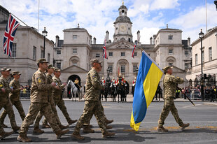 Soldaten laufen mit Fahnen der Ukraine eine Straße in London entlang