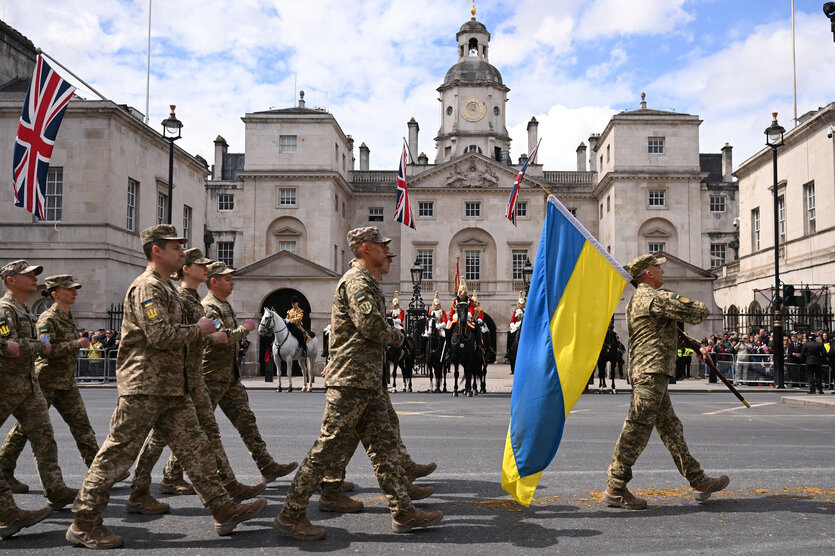 Soldaten laufen mit Fahnen der Ukraine eine Straße in London entlang