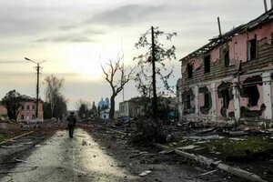 Ein Uniformierter steht auf einer Straße zwischen zerstörten Gebäuden