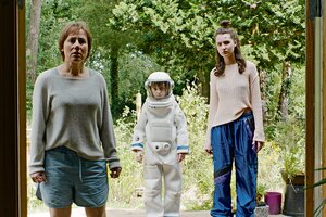 Die Schauspieler Eva Lübau, Theo Kretschmer und Lilli Lacher stehen in einer Filmszene auf einer Terrasse und blicken in ein Gebäude. Hinter ihnen sind grüne Pflanzen.