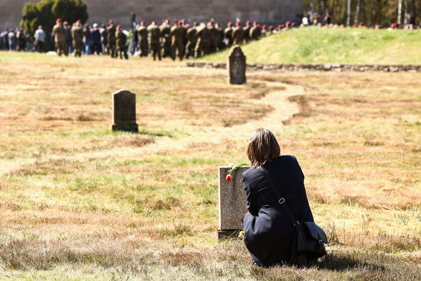 Eine Person kniet vor einem Gedenkstein