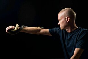 Eine Wasserkobra schlängelt sich um den ausgetsreckten Arm eines Mannes