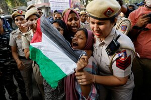 Indische Polizistinnen greifen eine junge schreiende Frau, die eine Palästinenserfahne vor sich gespannt hat