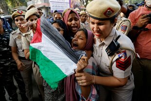 Indische Polizistinnen greifen eine junge schreiende Frau, die eine Palästinenserfahne vor sich gespannt hat