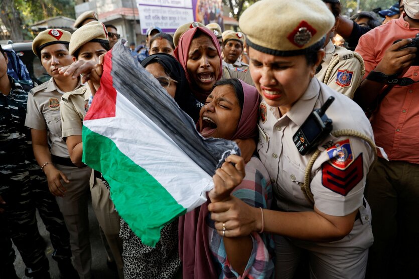 Indische Polizistinnen greifen eine junge schreiende Frau, die eine Palästinenserfahne vor sich gespannt hat