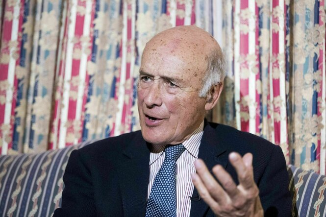 Porträt von Joseph Nye, er sitzt auf einem gemusterten Sessel vor einem gemusterten Vorhang und spricht - er trägt Krawatte und ein dunkles Jacket
