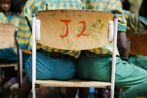Zwei Schüler sitzen auf einem Stuhl, es ist nur ein Ausschnitt zu sehen - von der Sitzfläche bis zur Stuhllehne