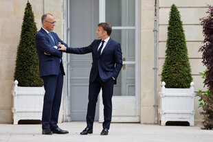 Merz und macron im Garten des Elysee Palastes, Macron legt eine Hand auf die verschränkten Arme von Merz