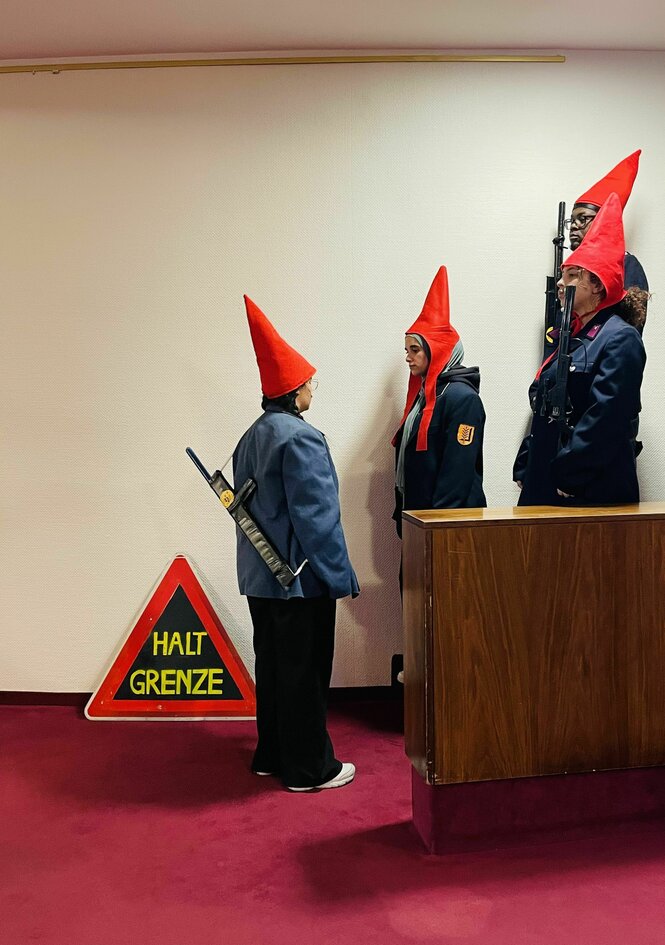 Zwerge mit Gewehren stehen vor einem Schild: Halt Grenze
