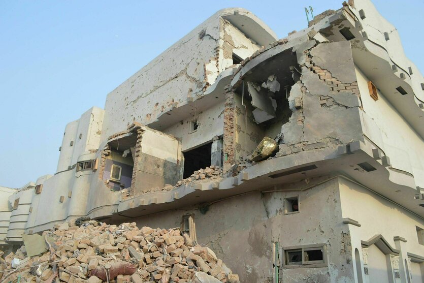 Nach einem Bombenangriff zerstörtes Gebäude, vor dem ein Haufen Schutt liegt