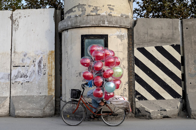 Eine Person auf einem Fahrrad transportiert viele Luftballons