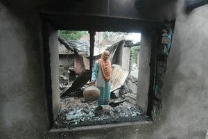 Eine Frau durchsucht Trümmer ihres Hauses