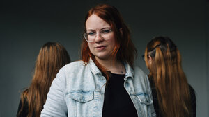 Drei Personen stehen zusammen, eine Person schaut an der Kamera vorbei, zwei wenden sich ab