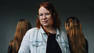 Drei Personen stehen zusammen, eine Person schaut an der Kamera vorbei, zwei wenden sich ab