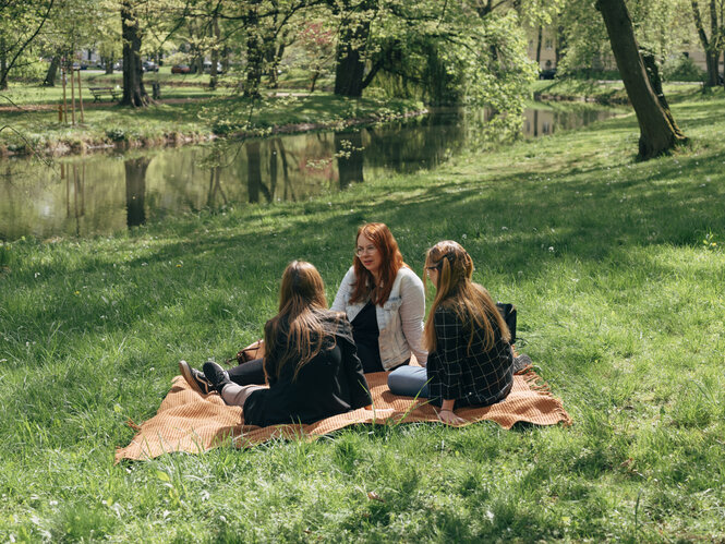 Drei Personen auf einer Picknickdecke.