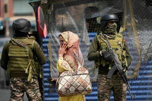 Zwei Soldaten in Uniform und eine Frau in Zivil stehen nebeneinander