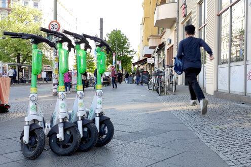 E-Scooter der Firma Lime stehen mitten auf einem Gehweg