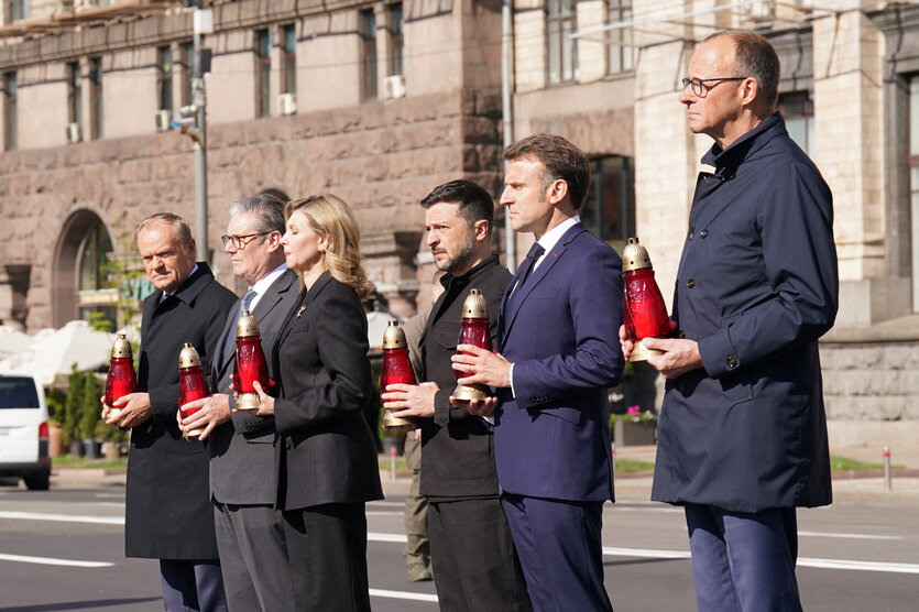 Bundeskanzler Friedrich Merz (v. r. n. l.), Frankreichs Präsident Emmanuel Macron, der ukrainische Präsident Volodymyr Selenskyj und seine Ehefrau Olena Zelenska, der britische Premier Keir Starmer und Polens Regierungschef Donald Tusk stehen in einer Reihe, sie halten jeweils eine Kerze in ihren Händen