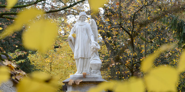 Friedhofsfigur in Herbstblättern