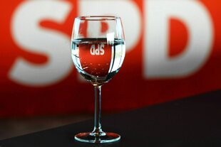 In einem Wasserglas spiegelt sich das Parteilogo der SPD
