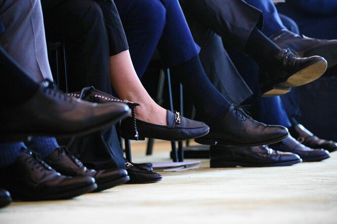Füße in Schuhen von vielen Männern und einer Frau