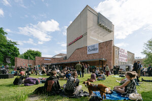 Menschen sitzen auf der Wiese um das besetzte Schauspielhaus Chemnitz herum