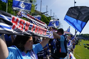 HSV-Fan hällt einen Schal mit der Aufschrift 