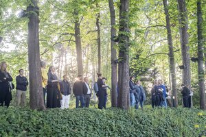 Besucher:innen stehen in der schmalen Kastanienallee im Garten des Haus der Wannsee-Konferenz und lauschen der Soundinstallation