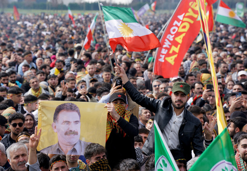 Menschen halten die krudische FAhnen hoch und ein Bild von Öcalan