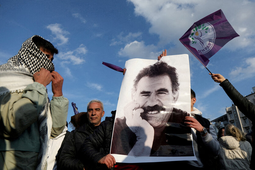 Ein Demonstrant hält eine Rauchfackel mit grünem Rauch und die Fahne der in einigen Ländern verbotenen Arbeiterpartei Kurdistans (PKK) hoch