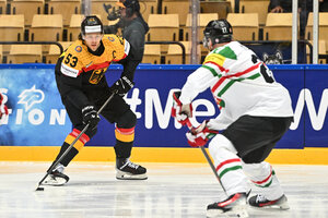 Zwei Eishockey-Spieler in voller Montur stehen sich auf dem Eis gegenüber, der Spieler im Trikot der deutschen Nationalmannschaft führt den Puck
