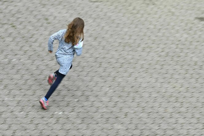 Eine Schülerin rennt auf einem Schulhof