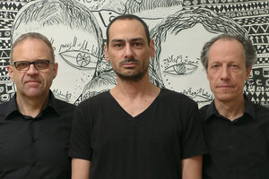 Das Trio Sawt Out steht vor einer Schwarz-Weiß-Zeichnung von Mazen Kerbaj. Die drei Männer tragen schwarze T-Shirts. Die Zeichnung im Hintegrund ist Wandgroß und lässt zwei Gesichter mit großen Augen erkennen.