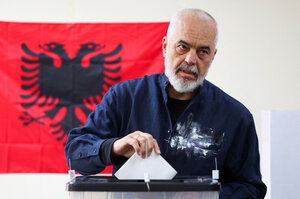 Edi Rama steckt seinen Wahlzettel in die Urne, dahinter eine albanische Flagge an der Wand