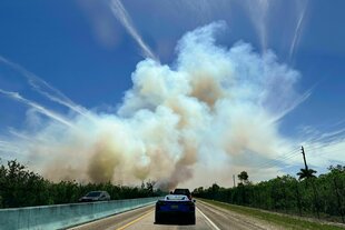 Fahrzeuge fahren auf dem Highway U.S. 1 in Richtung Süden, während der Rauch eines Buschfeuers in der Nähe von Homestead in den Himmel steigt.