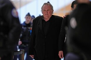 gerad depardieu in schwarzem anzug umgeben von polizei