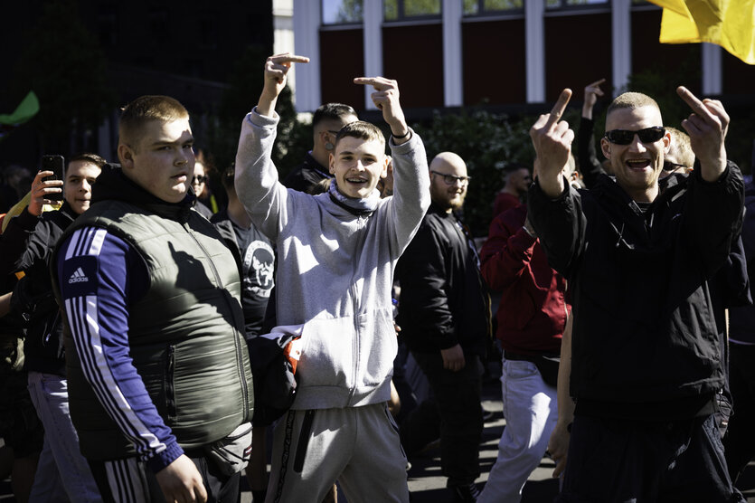 Rechte Demonstranten feixen und zeigen den Stinkefinger