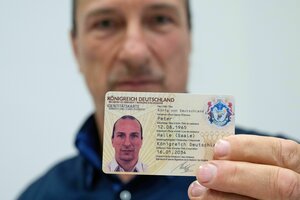 Peter Fitzek hält einen selbstgebastelten Personalausweis in den Händen