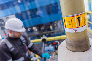 Ein Arbeiter mit Helm an einer Wasserstoffleitung