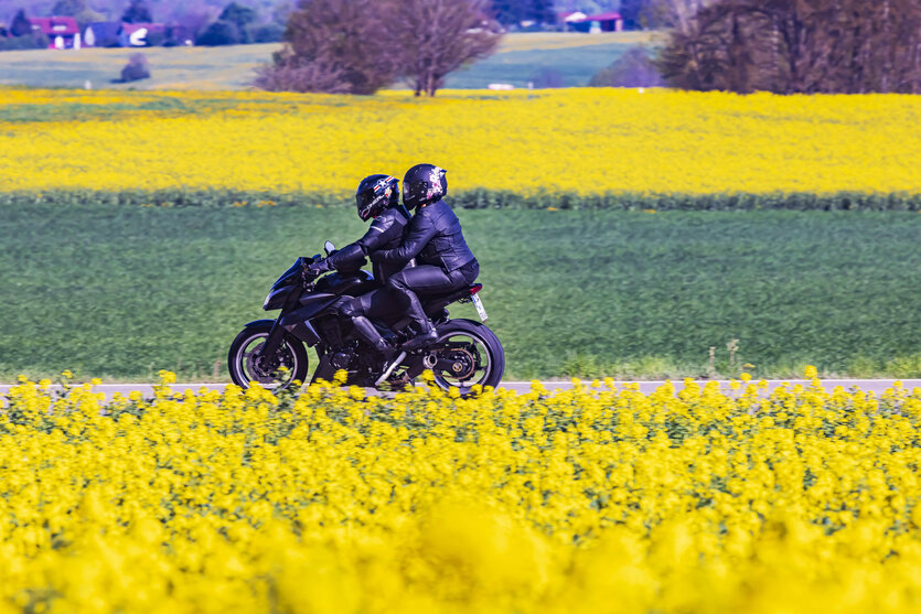 Zwei Personen fahre mit einem Motorrad auf einer Landstraße