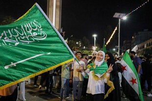 Menschen stehen lachen mit syrischen Fahnen auf der Straße