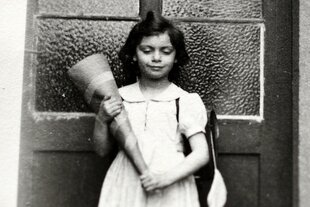 Historische Aufnahme von Bela Winkens, ein Mädchen steht mit einer Schultüte vor einer Haustür