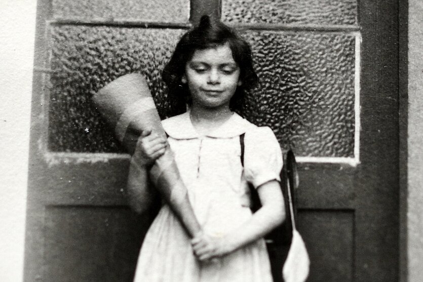 Historische Aufnahme von Bela Winkens, ein Mädchen steht mit einer Schultüte vor einer Haustür