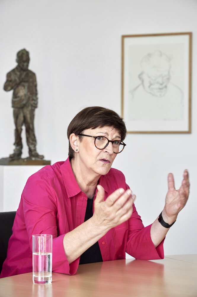 Saskia ESken sitzt an ihrem Schreibtisch und gestikuliert