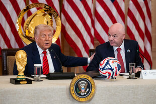 Trump und Infantino sitzen auf einem Podium. Im Hintergrund US-amerikanische Flaggen