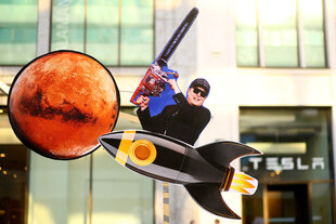 Ein Pappschild mit Elon Musk, Kettensäge und Weltkugel