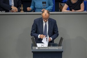 Friedrich Merz steh am Rednerpult im deutschen Bundestag und blättert in seinen Unterlagen