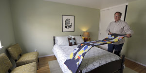 Ein Airbnb-Gastgeber macht die Betten in dem Zimmer, das er und sein Ehemann untervermieten